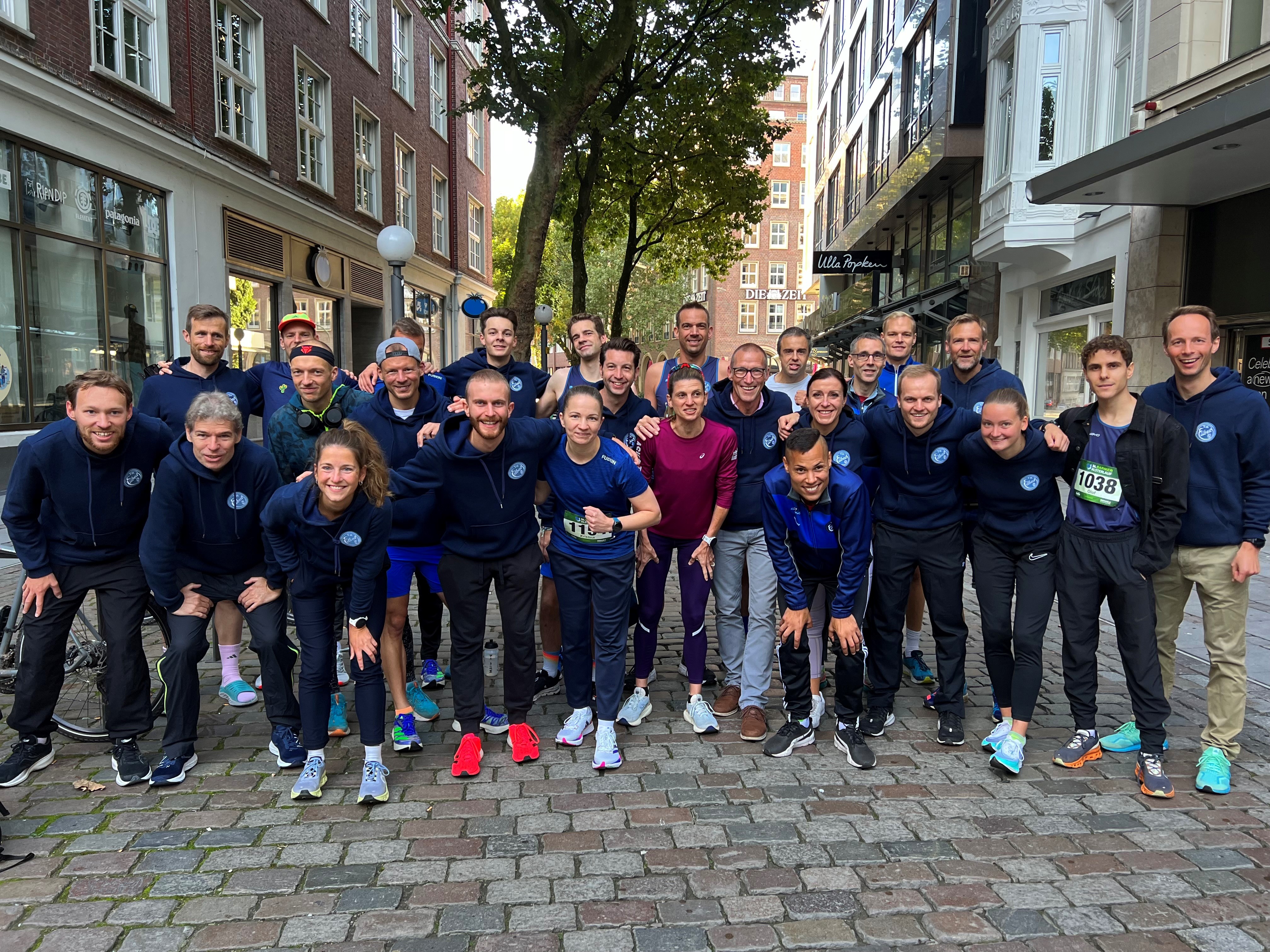 Gruppenfoto aller TEilnehmenden Laufteam-Mitgleider beim diesjährigen Bremer Alsterlauf. Alle sehen freundlich und meist lächelnd in die Kamera.