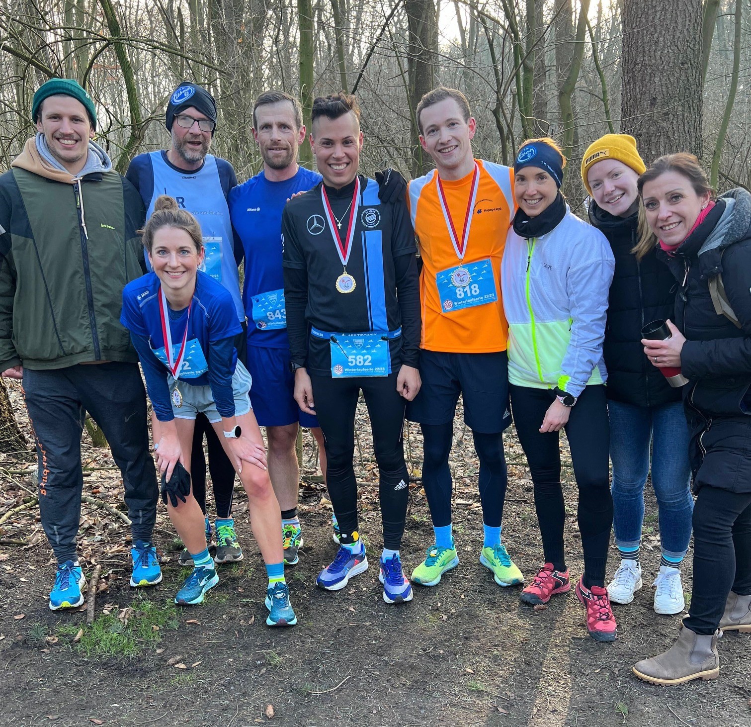 Gruppenfoto des Laufteams - Neun lächelnde Menschen teilweise in Sportkleidung, teilweise in Warmen Jacken.